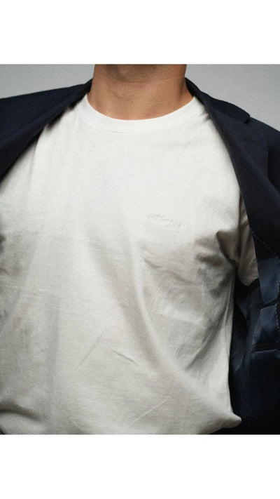 Man wearing a cloud white t-shirt essential with embroidery letters saying "wildest fig" 100% cotton