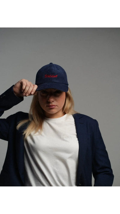 Woman wearing a corduroy navy blue baseball cap with a "wildest" red embroidery