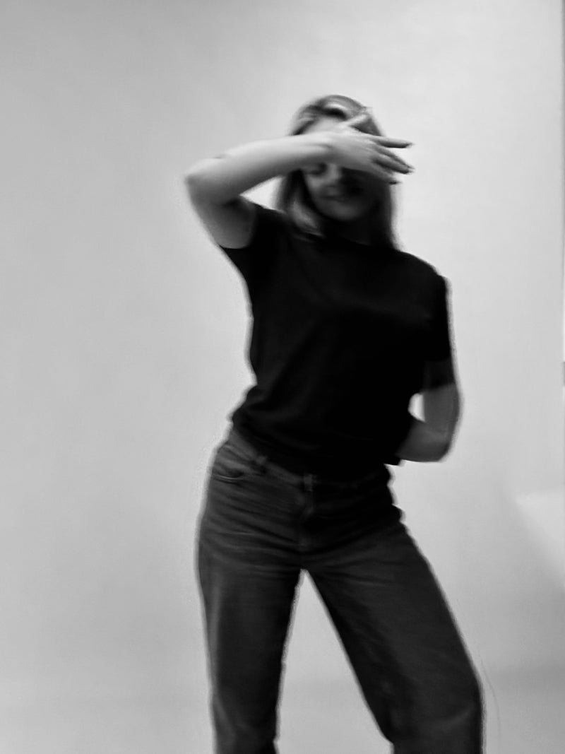 Person wearing a black t-shirt and dark pants against a plain background