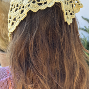 Person wearing a yellow crochet headband with blurred background for the wildest fig crochet collection
