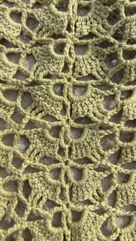 Close-up of a sage green crochet pattern of a bandana on a textured surface for the summer 2026 crochet collection of the wildest fig. made in portugal